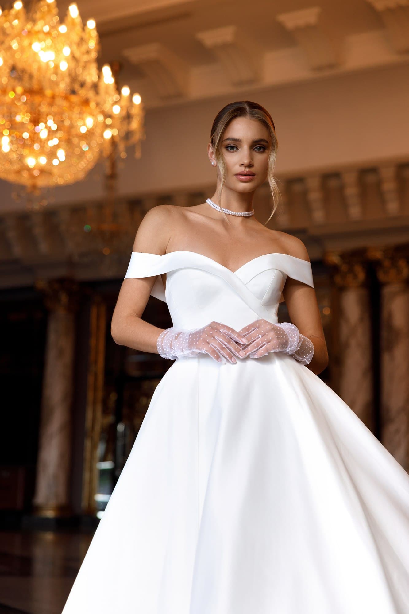 Romantic A-line wedding dress Mildred featuring an illusion corset, floral lace appliqués, flowing tulle skirt and elegant chapel train.